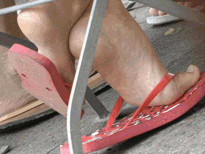 Blond girl dangling red rubber flip flops